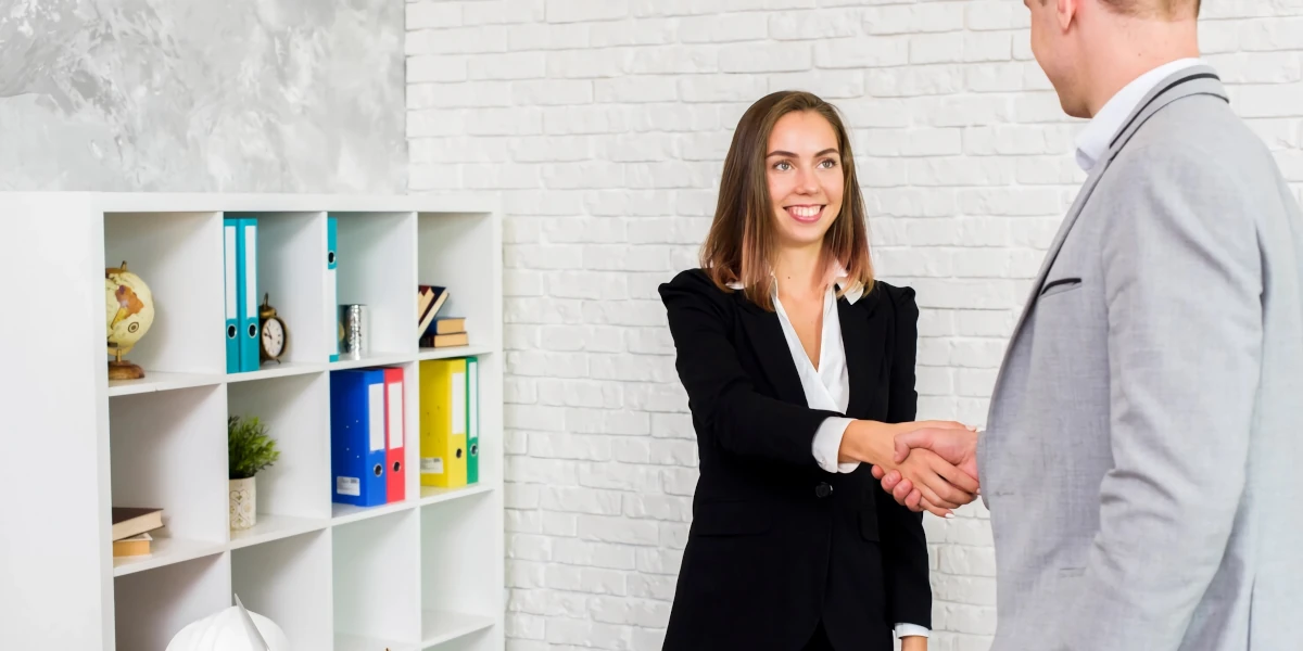 Woman in a suit shaking hands with a man in a suit